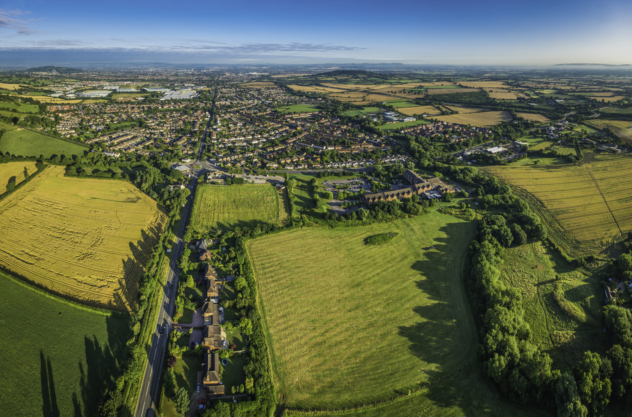 Aerial view over green fields pasture country town suburban housing